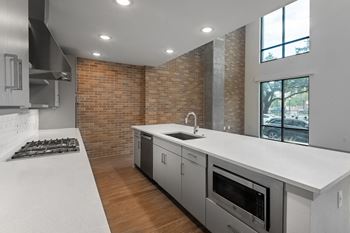 a kitchen with white countertops and a large window